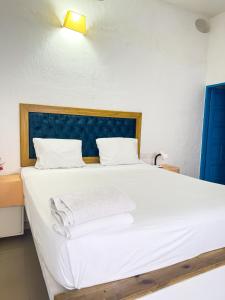 a bed with white sheets and towels on it at The Blue House Hostel in Santa Marta