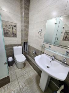 La salle de bains est pourvue d'un lavabo blanc et de toilettes. dans l'établissement Cozy apartment 2, à Samarcande