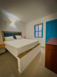 een groot wit bed in een kamer met een blauwe deur bij The Blue House Hostel in Santa Marta