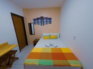 um quarto com uma cama com um cobertor colorido em Barra Grande Pousada em Maragogi