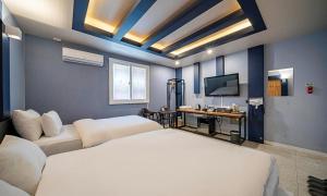 a bedroom with two beds and a desk and a television at Chungju Bali Hotel in Chungju