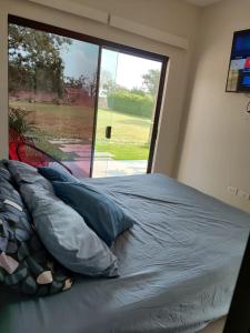 Bett in einem Zimmer mit einem großen Fenster in der Unterkunft Casa JARDIN I in Santa Cruz de la Sierra