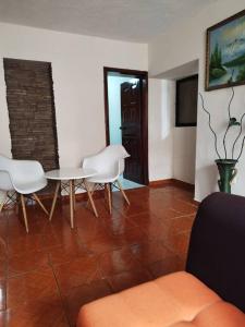 ein Wohnzimmer mit einem Tisch und weißen Stühlen in der Unterkunft Departamento Independiente completo, Centro Histórico Quito in Quito