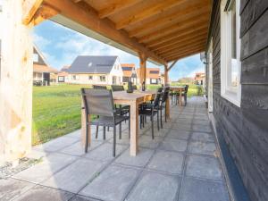 a patio with a wooden table and chairs at holiday home in Scherpenisse with sauna in Scherpenisse
