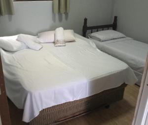 two beds in a room with white sheets and pillows at Casa Angra vista pro mar in Angra dos Reis