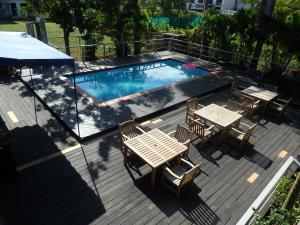 a deck with tables and chairs and a swimming pool at Bluewater Lodge in Nadi