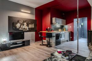 a living room with red walls and a kitchen at Cocon Sensuel - 50 Nuances - Les Cocons de Nath in Montbéliard