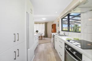 a kitchen with white cabinets and a large window at Poet's Corner in Rotorua
