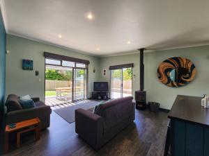 a living room with two couches and a television at The perfect Hahei bach - Dulop in Hahei