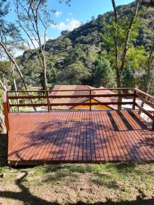 un banc en bois assis dans l'herbe avec une montagne dans l'établissement Seu Refúgio na Montanha Magnífica, à Santo Antônio do Pinhal