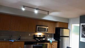 a kitchen with wooden cabinets and a black refrigerator at A lovely - 1 bedroom condo with swimming pool in Toronto