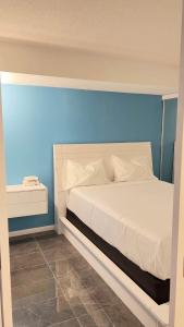 a bedroom with a white bed with a blue wall at A lovely - 1 bedroom condo with swimming pool in Toronto