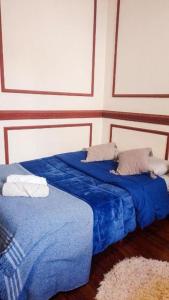 2 camas en una habitación con sábanas y almohadas azules en Dante y compañia en Buenos Aires