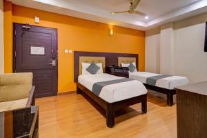 Duas camas num quarto com paredes amarelas em Udayee International Hotel em Tirupati