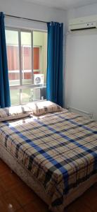 a bedroom with a bed with blue curtains and a window at Kitnet Mobiliada no centro de São Leopoldo. in São Leopoldo