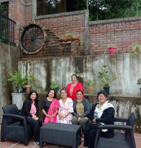 a group of women posing for a picture in front of a brick wall at EJ’s Frontyard- The Home Cafe & Stay in Kurseong