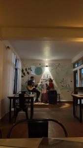 a room with a man playing a guitar and a woman singing at EJ’s Frontyard- The Home Cafe & Stay in Kurseong