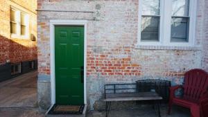 een groene deur en een bank naast een bakstenen gebouw bij The Green House w/ private ent in Brooklyn