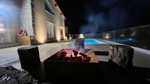 eine Feuerstelle vor einem Pool in der Nacht in der Unterkunft Villa Gerês Emblematico - Piscina & Jacuzzi in Venda Nova