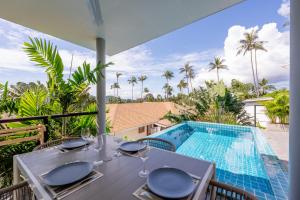 Hua Thanon BeachにあるVilla Léa 2 bedrooms pool wifi Netflixのバルコニー(スイミングプール付)のテーブル(ワイングラス付)