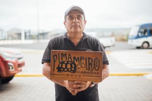 Een man met een bord dat pima mrror leest. bij Hotel Pimampiro in Puerto Baquerizo Moreno