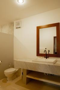 a bathroom with a sink and a toilet and a mirror at Uluwatu Stay's Standard Room #1 in Uluwatu