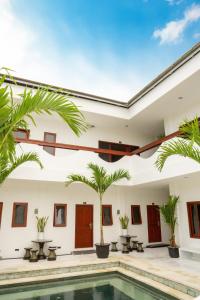 a villa with a swimming pool and palm trees at Uluwatu Stay's Standard Room #1 in Uluwatu