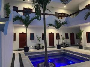 a room with a pool with palm trees in it at Uluwatu Stay's Standard Room #1 in Uluwatu