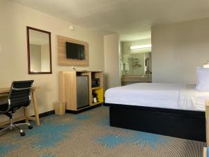 a hotel room with a bed and a desk and a chair at Days Inn by Wyndham Temple in Temple