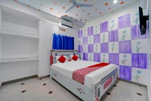 a bedroom with a white bed and a purple wall at OYO Flagship Hotel S Square Guest House in Patna