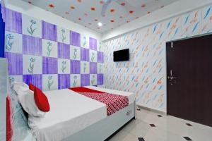 um quarto com uma cama e uma televisão na parede em OYO Flagship Hotel S Square Guest House em Patna