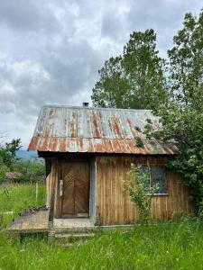 eine alte Holzhütte auf einem Grasfeld in der Unterkunft Bulgaria Countryside House Tiny Villa Cottage by Mountains of Kazanlak in Kasanlak