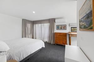 a bedroom with a bed and a dresser and a window at SHANGRI-LA ON SURF PARADE - FREE WIFI! in Inverloch
