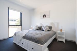 Un dormitorio blanco con una cama blanca y una ventana en Capel Sound Family Comforts on the Foreshore, en Rosebud