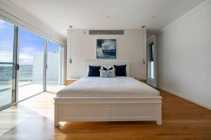 a white bedroom with a large bed and large windows at 'Starlight' A Slice of the Hollywood Hills in Bexley in Sydney