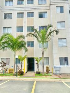 カンピーナスにあるApartamento aconcheganteの通りの前にヤシの木がある建物