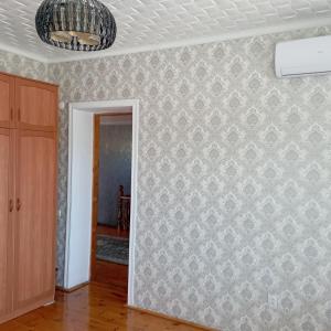 um quarto vazio com uma parede coberta de papel de parede em Канышай em Osh