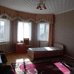 um quarto com uma cama, uma mesa e janelas em Канышай em Osh
