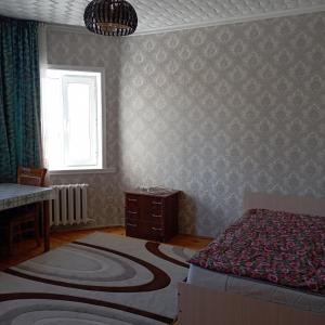 um quarto com uma cama, uma mesa e uma janela em Канышай em Osh