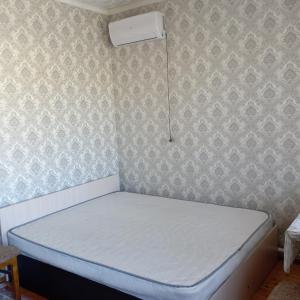 uma cama num pequeno quarto com um colchão branco em Канышай em Osh