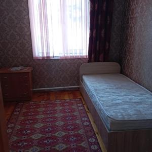 a bedroom with a bed and a rug and a window at Канышай in Osh