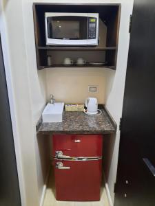 a small kitchen with a microwave and a red cabinet at Posada del Angú in Puerto Iguazú