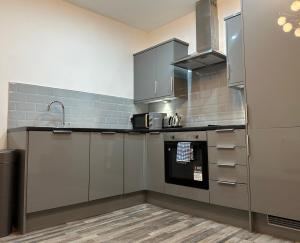 a kitchen with gray cabinets and a sink at Stylish Leeds City Apartment in Headingley