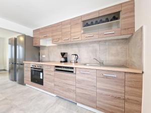 a kitchen with wooden cabinets and a stainless steel refrigerator at RAJ Living - 6 Room House with Terrace and Parking - 25 Min Messe DUS & Airport DUS in Duisburg