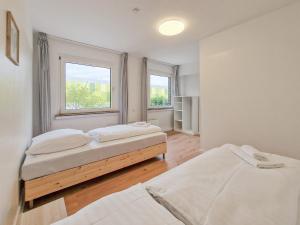 two beds in a room with two windows at RAJ Living - 6 Room House with Terrace and Parking - 25 Min Messe DUS & Airport DUS in Duisburg