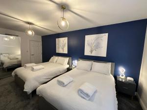 two beds in a room with blue walls at Stylish Leeds City Apartment in Headingley