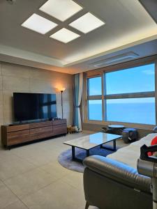 sala de estar con sofá y TV de pantalla plana en Eastern View Premium Residence, en Ulsan