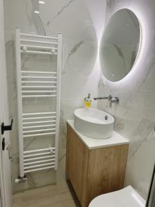 La salle de bains blanche est pourvue d'un lavabo et d'un miroir. dans l'établissement BlueLine apartment 2, à Loutraki