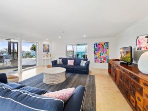 a living room with a blue couch and a tv at First Point Down by Discover Stradbroke in Point Lookout