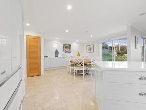 a white kitchen with a table and a dining room at First Point Down by Discover Stradbroke in Point Lookout